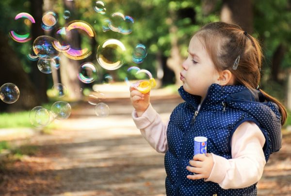 niña que aprende mientras juega con burbujas